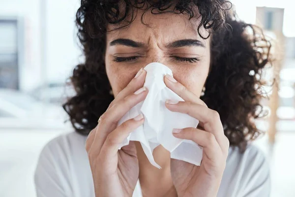 Black woman, tissue and nose with flu in home with self care, health and sneeze by blurred background. Gen z girl, toilet paper and sick with allergy, covid and closeup in house, apartment or room.