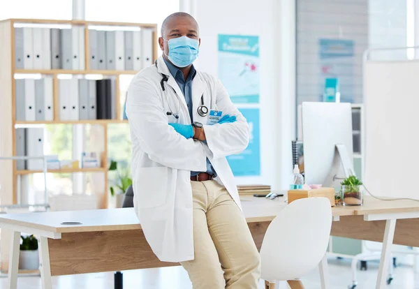 Proud african american doctor arms crossed. Medical professional wearing a mask to protect from covid. Doctor keeping safe from corona in his office. portrait of confident physician in his office.