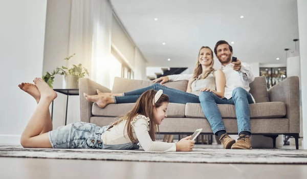 Happy family, relax or child on tablet in living room, house or home live streaming, movies channel or internet show bonding. Smile, parents or kid girl on technology, television or watching tv media.