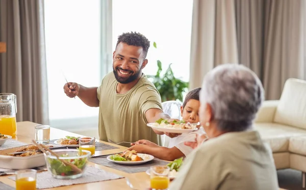 Closeup of a mixed race family having lunch at a table in the lounge at home and smiling while having a meal together.