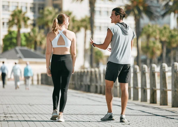 Fitness, teamwork or health with a runner couple on the promenade for cardio or endurance from the back. Exercise, wellness or workout with a man and woman athlete running outdoor in the city.