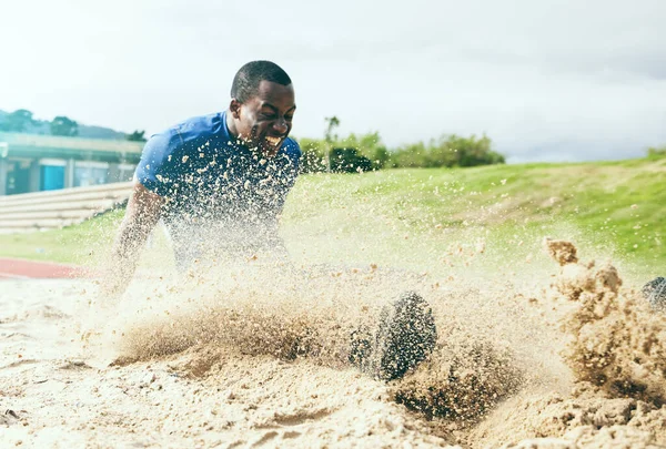 Long jump, fitness and black man in the sand for sports, exercise and competition in the USA. Energy, speed and African athlete training for a sport challenge, jumping and landing with power.