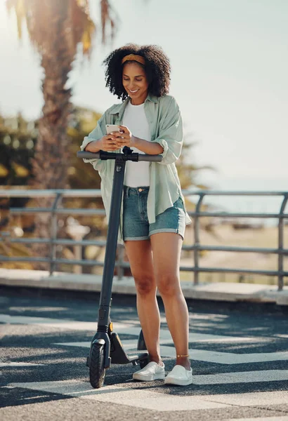 Travel, scooter and black woman with phone in city for social media, texting or web scrolling. Technology, communication and female with electric moped and mobile smartphone for networking in street