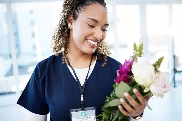Achievement, celebration and a doctor with flowers at a hospital for a promotion and gift for work. Care, happy and female nurse with a bouquet as a present for promotion in healthcare nursing job.