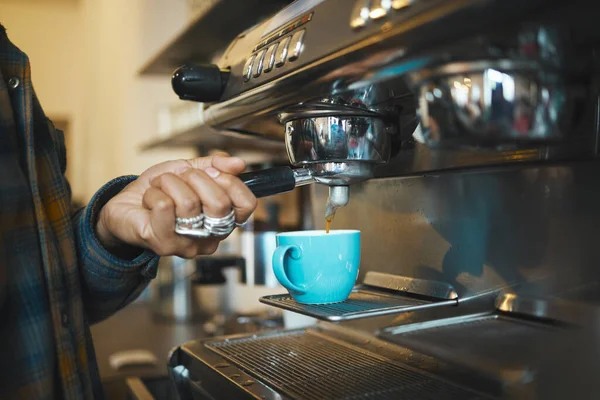 Coffee shop machine handle, hand of barista brewing espresso in restaurant and closeup of hot water beverage in cafe. Caffeine drink in mug, person holding tool on morning in kitchen and breakfast.