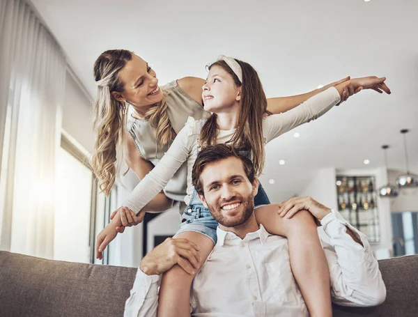 Happy family, bonding or airplane game in living room, house or relax home in freedom activity, energy or fun play games. Smile, parents or child in flying on father shoulders in fantasy or support.