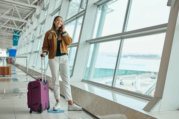 Phone call, travel and woman with luggage at airport, chatting or speaking to contact in lobby. Suitcase, mobile and happy female with smartphone for networking while waiting for flight departure