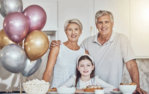 Portrait, grandparents or girl in celebration of a happy birthday in house party or kitchen with popcorn or cake. Grandmother, old man or child bonding with love or care in family home to celebrate.