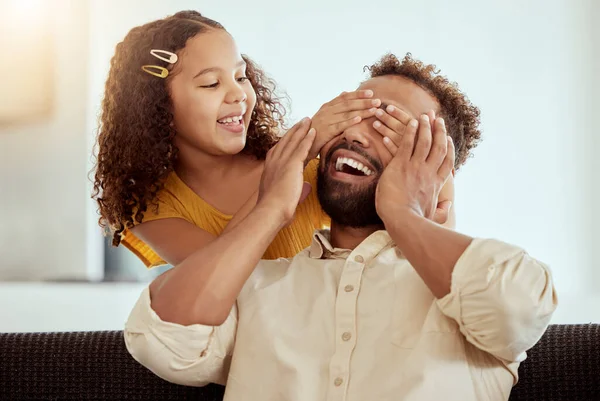 Mixed race single father and daughter feeling playful in home living room. Smiling hispanic girl bonding and covering single parents eyes in lounge. Happy man and child playing hide and seek toget.