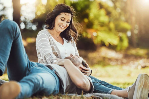 Love, relax and couple at park, laughing at funny joke or comic comedy and having fun together outdoors. Valentines day, romance cuddle and care of man lying on lap of happy woman on romantic date