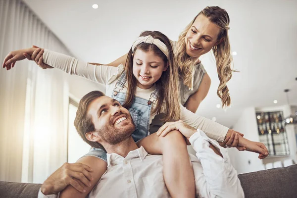 Family, bonding and airplane game in living room, house or relax home in freedom activity, kids energy or fun playing. Smile, happy and flying child on father shoulders in fantasy support with mother.