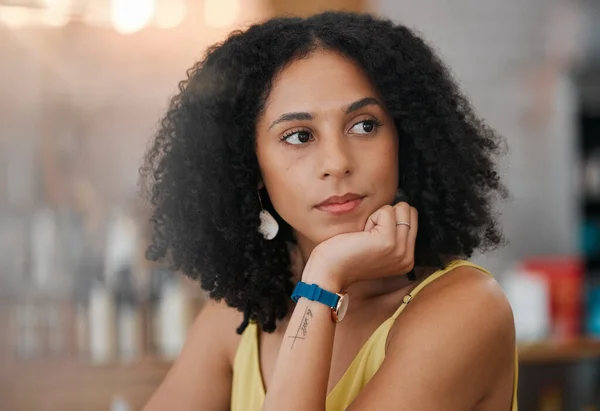 Black woman, face and thinking in cafe for business idea, vision or wondering in thought waiting for service. African American female contemplating in wonder sitting relaxed indoors at a coffee shop.