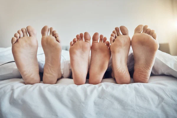 Family feet, bed and together with kid, parents and sleeping on holiday for bonding, care and happiness. Bedroom, people and sleep with mom, dad and child on vacation to relax, break and hospitality.