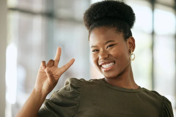 Happy optimistic african american business woman gesturing peace. Playful young female entrepreneur showing victory sign in an office.