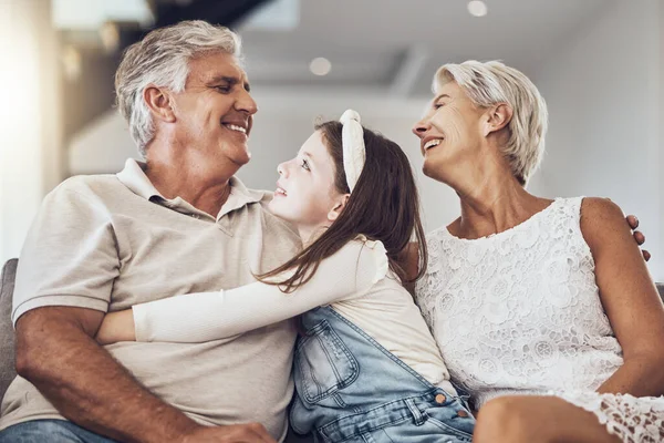 Relax, love or grandparents hug a girl in living room bonding as a happy family in Australia with care. Retirement, smile or elderly man relaxing old woman with child at home together on fun holiday.