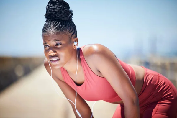 Tired, breathing and black woman training for fitness, healthy target and body fatigue. Female athlete, break and breathe for sports workout, running and exercise with music earphones for challenge.