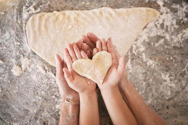 Top view, hands and heart with parent baking with kid, teaching and bonding together, weekend break and loving. Love, family or in kitchen with dough, love or child development with skills or support.