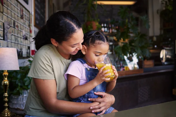 Coffee shop, black family and hug with a mother and daughter enjoying a beverage in a cafe together. Hugging, caffeine and love with a young woman and happy female child bonding in a restaurant.