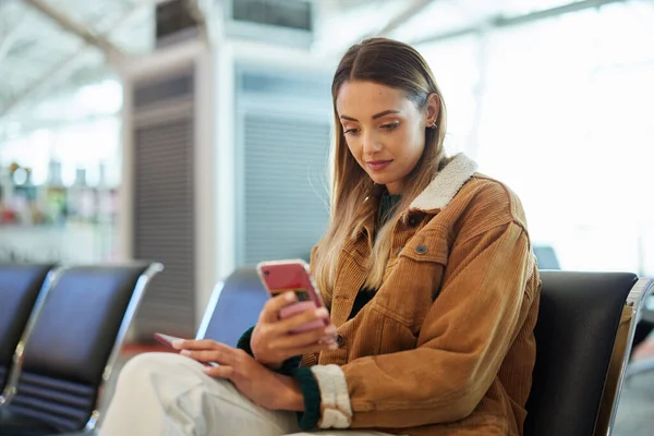 Travel, phone and woman relax at airport lobby on social media, internet browsing or web scrolling. Immigration, mobile technology and female with smartphone for networking while waiting for flight