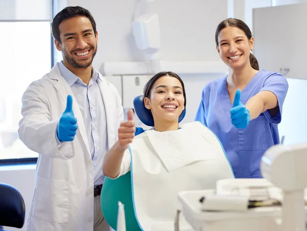 Best dental practice in the business. Portrait of a young woman showing thumbs up while visiting the dentist