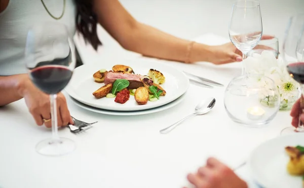 stock image Couple, table and food at restaurant in closeup for valentines day date, bonding or romance in night. Man, woman and red wine glass with fine dining, service and hands for dinner, love or celebration.