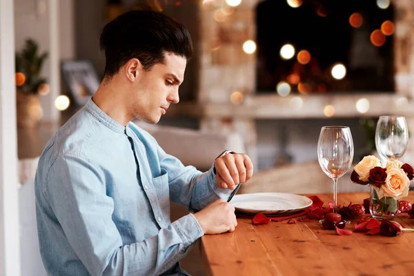 Date, watch and man waiting while in the restaurant for valentines day checking the time. Fine dining, late and upset guy by the table for a dinner reservation for anniversary or romantic event