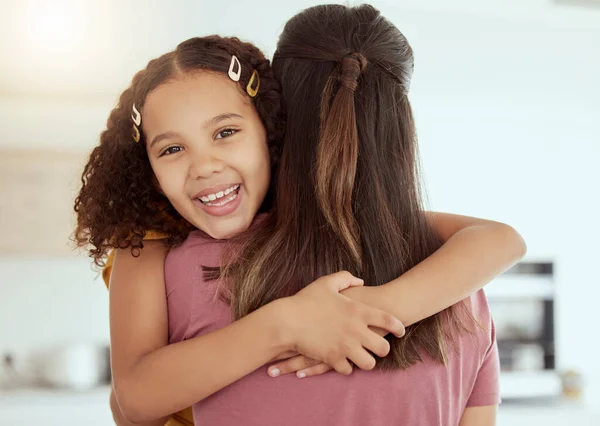 Portrait of mixed race single mother and daughter hugging in living room at home. Smiling hispanic girl embracing single parent and bonding in lounge. Happy affectionate child and woman on a weekend.