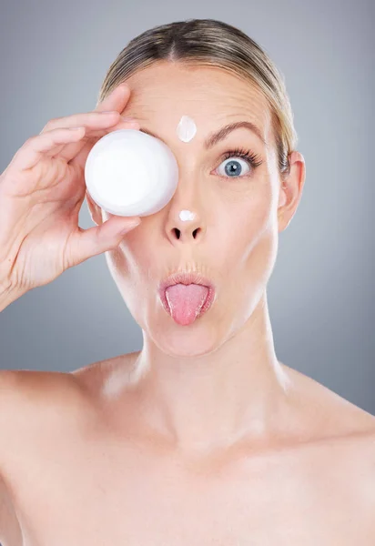 There are no harsh or ugly chemicals in here. Studio portrait of an attractive mature woman applying moisturiser on her face against a grey background