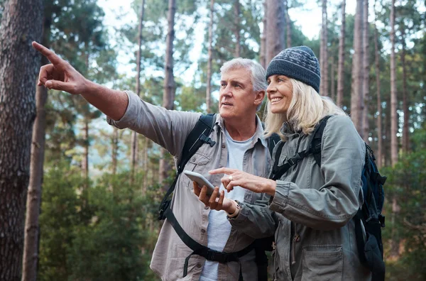 Finding our way with the help of a digital compass. a mature couple using a cellphone while out on a hike together