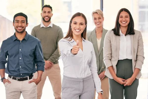 Well get the job done perfectly for you. an attractive young businesswoman standing in the office with her colleagues and showing a thumbs up