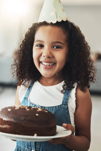 Portrait of happy girl with birthday cake, child in home and surprise celebration in Atlanta house alone. Young kid with smile in homemade chocolate dessert, hat on curly hair and excited african.
