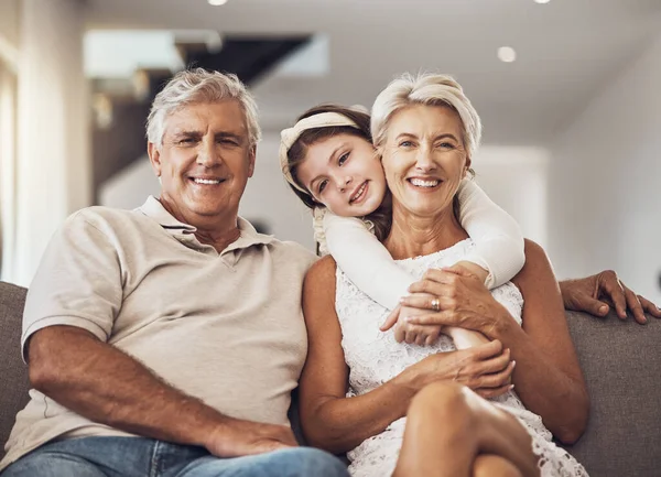 Love, portrait or grandparents hug a girl in living room bonding as a happy family in Australia with care. Retirement, smile or elderly man relaxing old woman with child at home together on holiday.