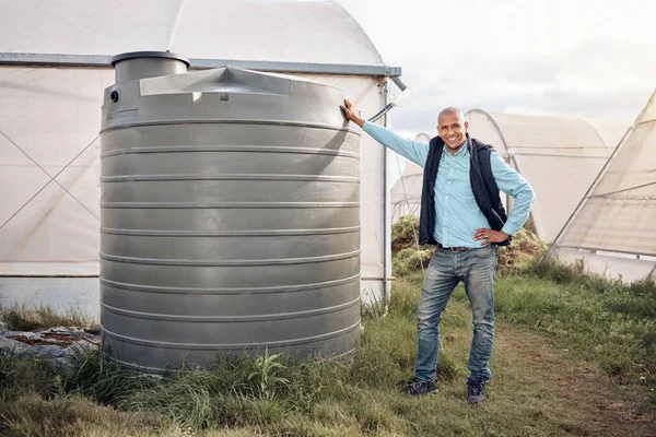 Man, portrait and water tank in farming liquid or soil hydration for vegetables, food and crops growth. Irrigation, storage and agriculture container for watering conservation, smile or happy farmer.