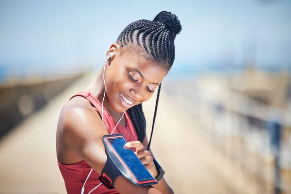 Black woman, runner and arm band with phone, earphones and motivation for outdoor fitness. Happy female athlete, mobile music and training for exercise wellness, workout energy and sports technology.