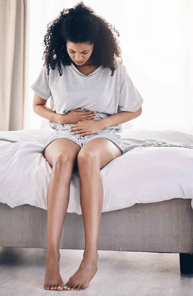 Black woman, stress or stomach ache on house bed, home or bedroom in period pain, menstruation cramps or ibs crisis. Hurt person, injury or abdomen tummy in healthcare emergency or appendicitis risk.