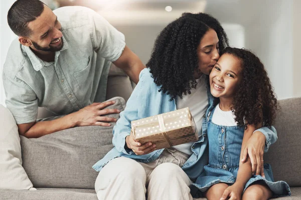 Birthday, kiss and child with gift from parents to celebrate a special occasion, achievement or event. Affection, gratitude and mom kissing a child while giving a present from dad for celebration.