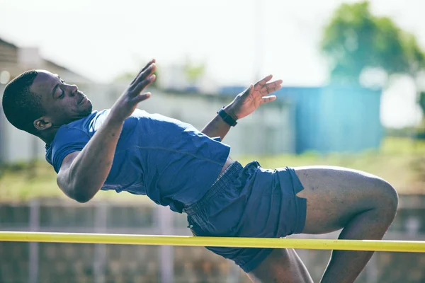 Man, high jump and fitness or athletics at a stadium for training, energy and cardio against sky background. Jumping, athlete and male outdoors for performance, endurance and competition on mock up.