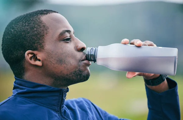 Fitness, health and side profile of black man drinking water to hydrate after running, exercise and workout. Healthy, sports and African athlete with a drink after training and cardio in Germany.