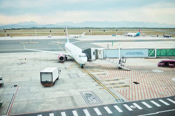 Airplane at airport, stationary aircraft on tarmac and runway for international passenger travel on sky horizon. Plane on ground, outdoor flight terminal and cargo carrier on aeroplane runway.