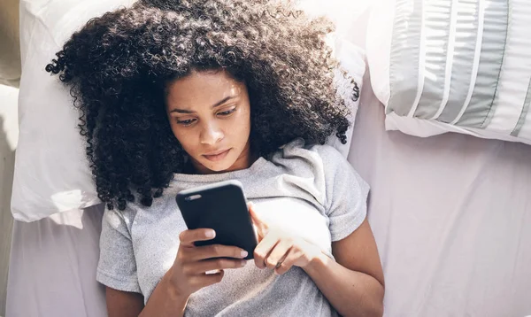 Phone, black woman and top view in home bedroom for social media, texting or internet browsing in the morning. Technology, bed relax and female with mobile smartphone for web scrolling or networking