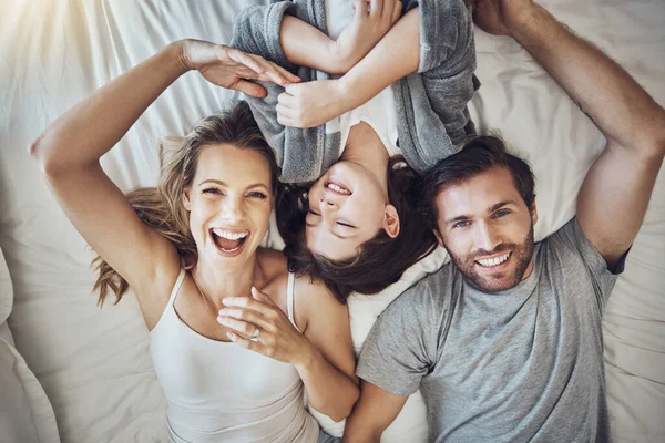 Happy family relax together, parents and child in bed on the weekend, break with love, care and bonding at home. Portrait, happiness and joy, man, woman and girl laugh and peace with quality time.