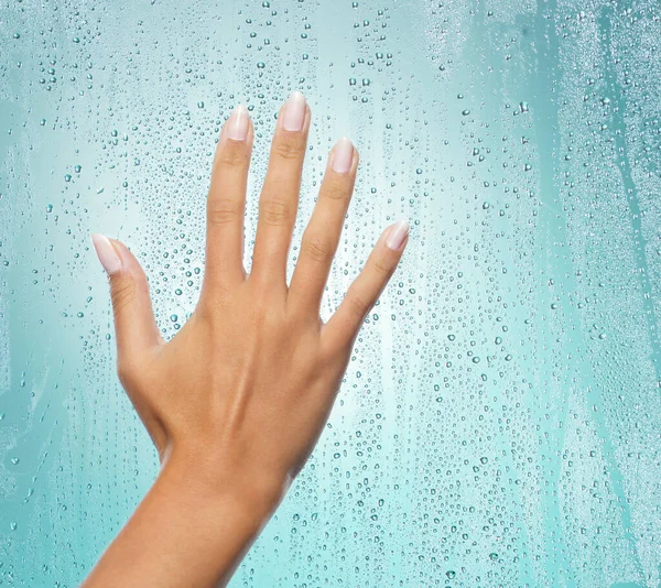 Soft as silk. a unrecognizable hand on glass against a blue background