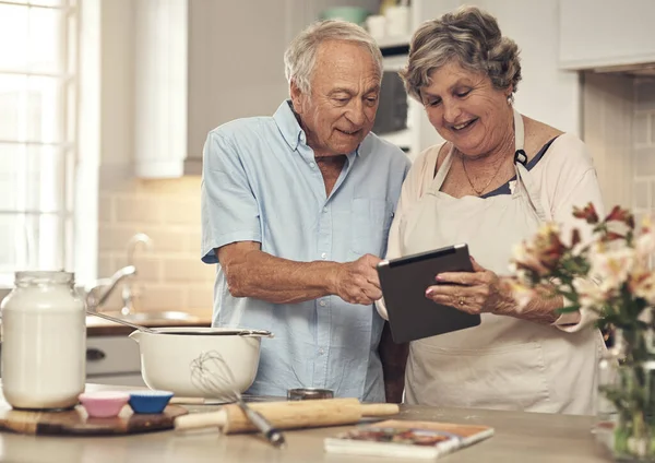 I found all these recipes online. a senior couple using a digital tablet while baking at home