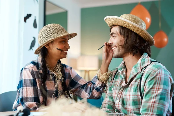 Makeup just makes it so much better. a young woman applying makeup to a young man at home