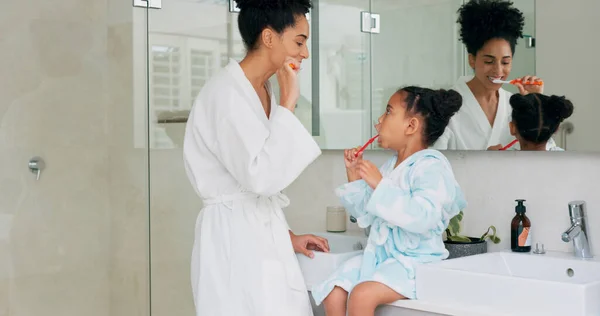 Dental, bathroom and mother and child brushing teeth for oral health, teeth healthcare and cleaning mouth with toothbrush. Black family morning routine, toothpaste and mom teaching self care hygiene.