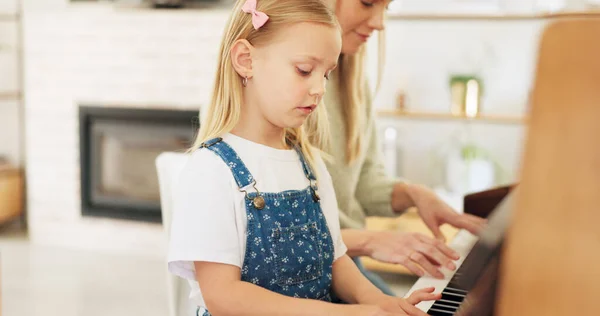 Music development, girl learning piano and musical note education from mom in the home living room. A child musician playing keys, learn creative audio art and fun concert performance in family house.