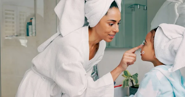 Home spa, mother and child doing morning beauty cleaning with family product for dermatology, cosmetic and skincare. Black woman and girl happy for wellness, health and skin cream or mask in bathroom.