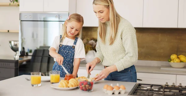 Breakfast, morning and mother and kid cooking, help or prepare croissant meal, fruit or food in home kitchen. Love, happy family and youth girl with mom, mama or woman enjoy fun quality time and bond.