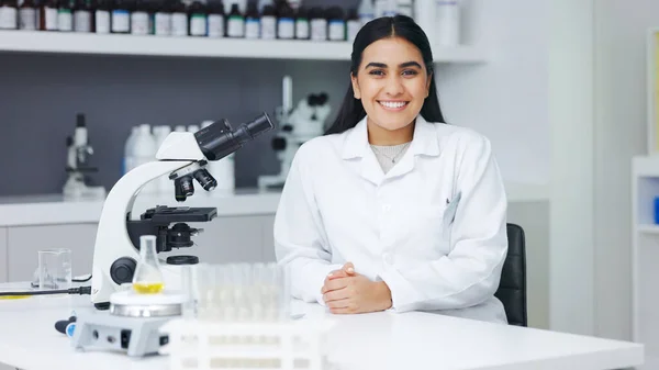 Portrait of a female scientist using a microscope in a research lab. Young biologist or biotechnology researcher working and analyzing microscopic samples with the latest laboratory tech equipment.