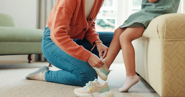 Mother, child and shoes in preparation for school, learning or education in the bedroom at home. Mom helping little girl with shoe getting ready for academy, college or elementary at the house.